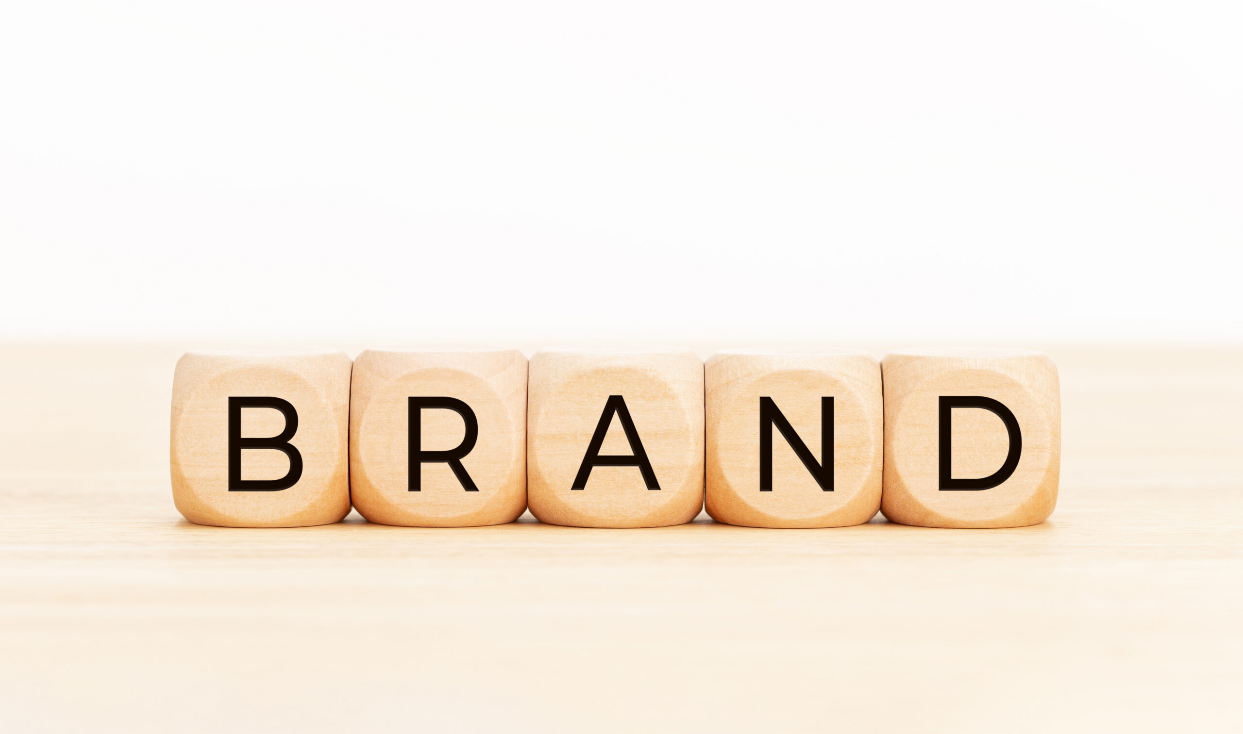 Wooden blocks are arranged in a row spelling the word “BRAND.”