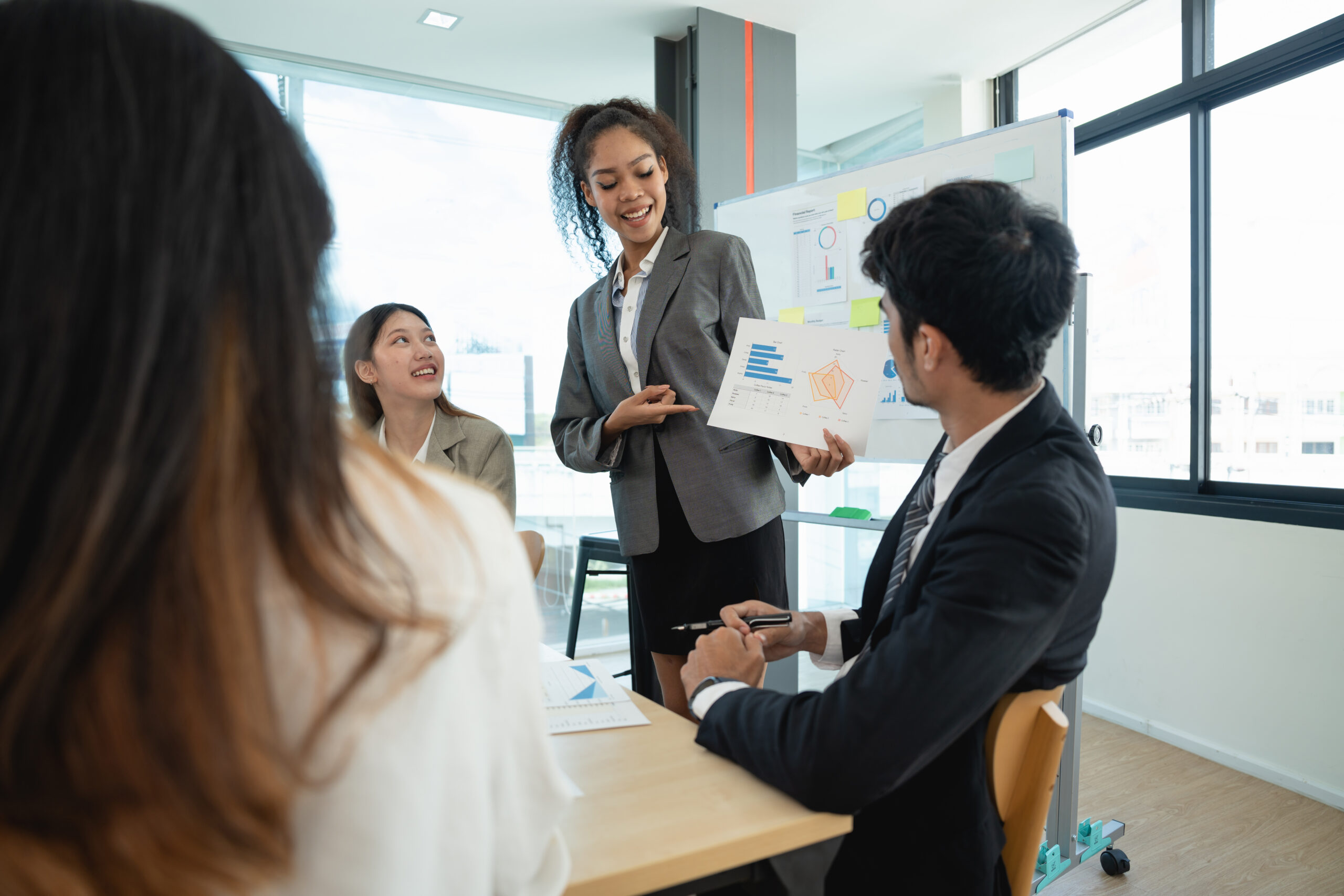 A female team lead presenting sales and marketing solutions to her team members.